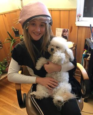 girl in salon chair holding dog 
